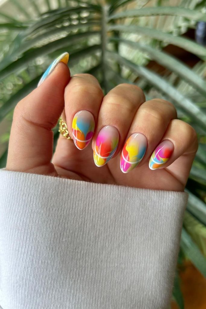 Kreatives Nageldesign mit bunten Regenbogenfarben und geometrischen Mustern.