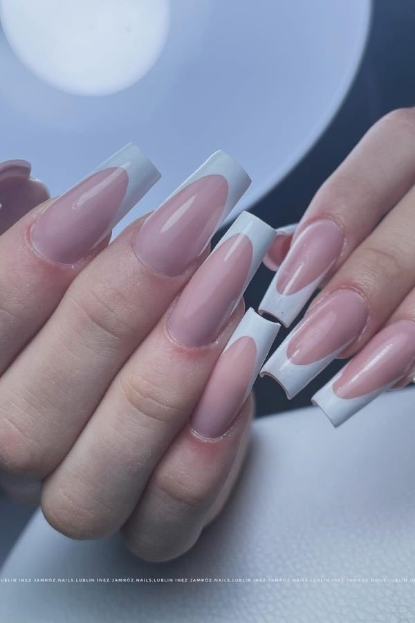 Lange mandelförmige French Nails mit breitem weißen Rand und glänzendem Finish, modernes und elegantes Design.