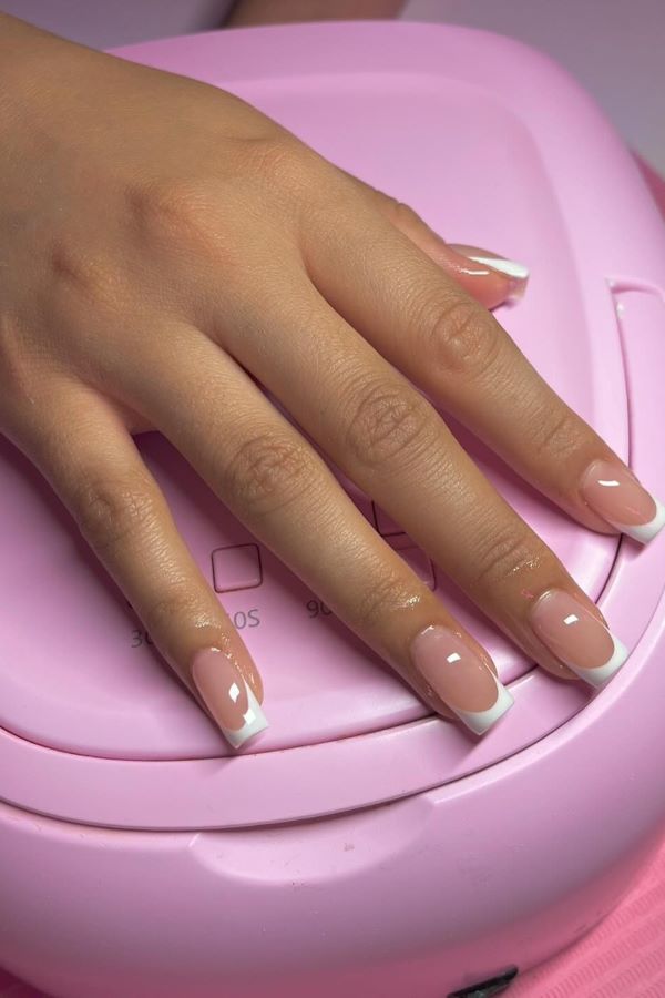  Kurze, quadratische Nägel mit einem klassischen French Manicure-Stil, akzentuiert mit geometrischen Linien in Weiß und Schwarz.