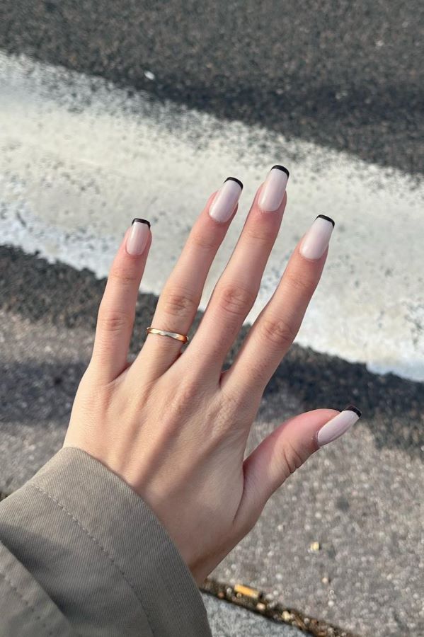 Hand mit Ballerina-Nägeln im minimalistischen French-Design mit schwarzer Spitze.